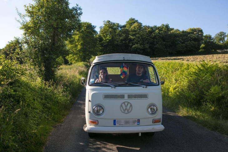Van getaway on a nature road for an early booking couple Couple driving a retro van on a small countryside road, showing the ease of early booking couple.
