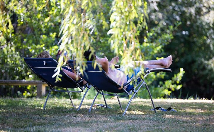 Relaxing in nature loungers for an early booking couple Couple lying on shaded loungers in nature, peaceful moment showing the benefits of early booking couple.