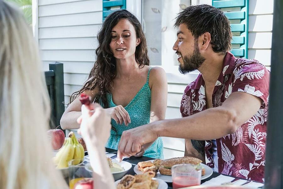 Group of friends sharing a meal at the campsite on the terrace of their mobile home