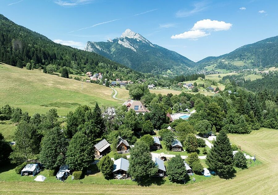 Aerial view of a nature campsite in Isère surrounded by forest and mountains, near the Chartreuse range